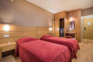 two beds in a hotel room with red blankets at Hotel Botanico in Lisbon