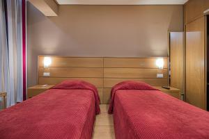 two beds in a bedroom with red blankets at Hotel Botanico in Lisbon