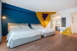 twee bedden in een slaapkamer met een blauwe muur bij HOODY ACTIVE & HAPPINESS HOTEL in Arco