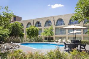 a pool in front of a building with chairs and an umbrella at Fiesta Inn Aeropuerto CD Mexico in Mexico City