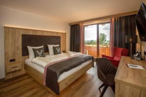 a bedroom with a bed and a desk and a window at Steig-Alm Hotel Superior in Bad Marienberg