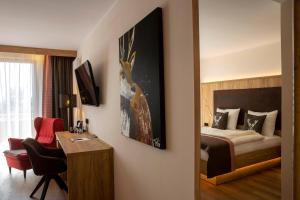 a hotel room with a bedroom with a bed and a desk at Steig-Alm Hotel Superior in Bad Marienberg