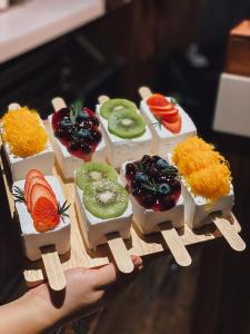 a hand holding a plate of food with fruit on it at Westory Design Poshtel in Kanchanaburi City