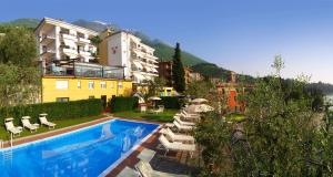 un hôtel avec une piscine, des chaises et un bâtiment dans l'établissement Hotel Capri, à Malcesine