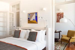 1 dormitorio con 1 cama blanca y 1 silla en Casa Balthazar, en Lisboa