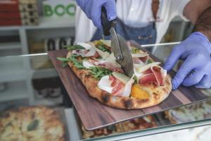 a person cutting a pizza with a pair of scissors at Hotel Continental in Reggio di Calabria