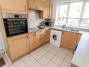 - une cuisine avec des placards en bois et un lave-linge dans l'établissement Crooked Well, à Bath