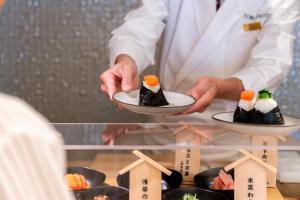 a chef is holding two plates of sushi at Asakusa Tobu Hotel in Tokyo