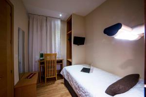 Habitación de hotel con 2 camas, escritorio y lámpara en Hotel Serrano, en Córdoba