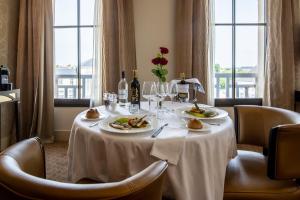 - une table avec deux assiettes de nourriture et des verres à vin dans l'établissement Jehan De Beauce - Teritoria, à Chartres