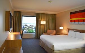 um quarto de hotel com uma cama grande e uma janela em Stamford Plaza Sydney Airport Hotel & Conference Centre em Sidney