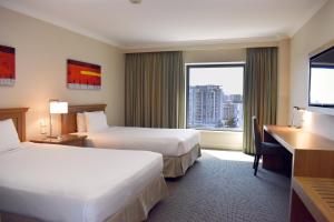 um quarto de hotel com duas camas e uma secretária e uma janela em Stamford Plaza Sydney Airport Hotel & Conference Centre em Sidney