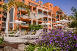 a building with chairs and umbrellas in front of it at Arguineguín Park By Servatur in La Playa de Arguineguín