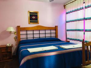 a bedroom with a blue bed with two towels on it at Hotel Cazomalli Oaxaca in Oaxaca City