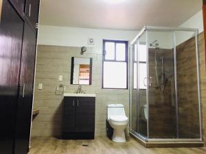 a bathroom with a toilet and a glass shower at Hotel Cazomalli Oaxaca in Oaxaca City