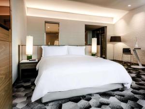 um quarto com uma grande cama branca e um espelho em Sofitel Mexico City Reforma em Cidade do México