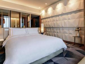 um quarto com uma grande cama branca e uma parede em Sofitel Mexico City Reforma em Cidade do México