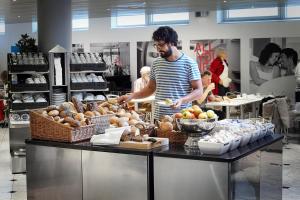 Ein Mann bereitet Essen in einer Bäckerei vor. in der Unterkunft Cabinn City in Kopenhagen