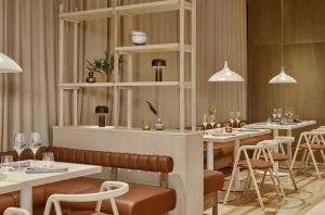 un ristorante con tavoli e sedie bianchi e luci di VALO Hotel & Work Helsinki a Helsinki