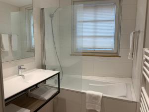 a bathroom with a sink and a tub and a window at Hôtel Restaurant Au Boeuf in Blaesheim