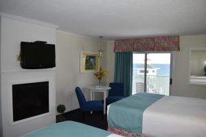 ein Hotelzimmer mit einem Bett, einem Kamin und einem TV in der Unterkunft Breakers Resort - Lakeside in Saint Ignace