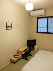 - une chambre avec un lit, un bureau et une télévision dans l'établissement Guesthouse Engawa, à Kyoto