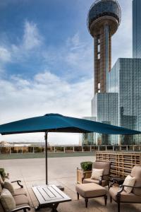 een grote blauwe parasol op een patio met stoelen en een toren bij Hyatt Regency Dallas in Dallas