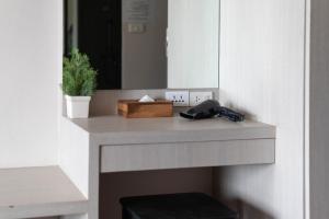 a bathroom counter with a mirror and a phone on it at The Pino Hotel Pakchong in Pak Chong