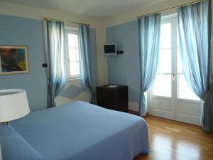 a blue bedroom with a bed and two windows at Hotel Residence La Luna Nel Porto in Stresa