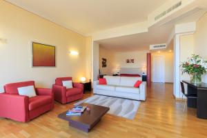 a living room with a white couch and two red chairs at Hotel Residence La Luna Nel Porto in Stresa