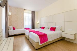 a hotel room with two beds with pink pillows at Hotel LX Rossio in Lisbon