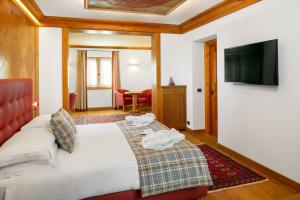 a hotel room with a bed and a flat screen tv at Hotel Natale in Cortina dʼAmpezzo