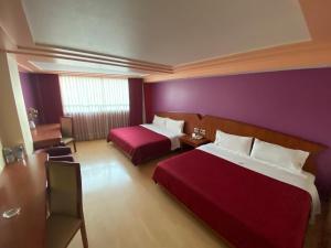 a hotel room with two beds and a purple wall at HOTEL MARIA RICO in Mexico City