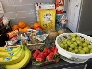 a counter with a bunch of fruit and a bowl of strawberries at Luxury Rooms near Temple U, Drexel, UPenn, and the MET in Philadelphia