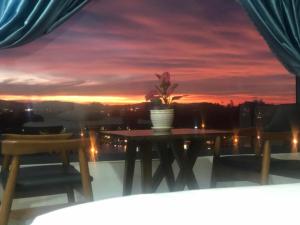 une table avec une plante en pot sur un balcon avec un coucher de soleil dans l'établissement Luan'S Villa, à Đà Lạt