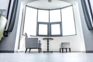 um quarto com duas cadeiras e uma mesa e uma grande janela em Hôtel Sancta Maria em Lomé