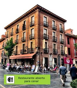 a large brick building with people sitting outside of it at Hotel Spa QH Centro León in León