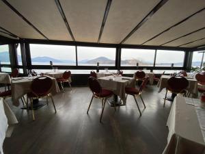 ein Restaurant mit Tischen und Stühlen und großen Fenstern in der Unterkunft Hotel Concorde in Arona