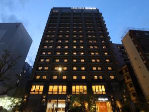 東京的住宿－Dormy Inn Ikebukuro，一座高大的黑色建筑,有许多窗户