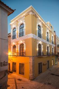 ein gelbes Gebäude mit Fenstern und Balkonen auf einer Straße in der Unterkunft Day Off Suite&Hostel in Setúbal