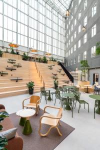 una grande stanza con tavoli, sedie e scale di VALO Hotel & Work Helsinki a Helsinki