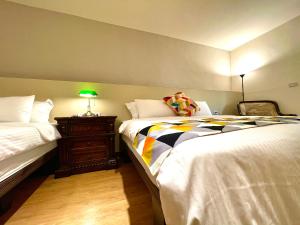 a bedroom with two beds and a table with a lamp at 墾丁聚點旅棧 2Ps Hotel in Kenting