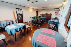 a restaurant with blue tables and chairs in a room at ペンション木もれ日 in Ito