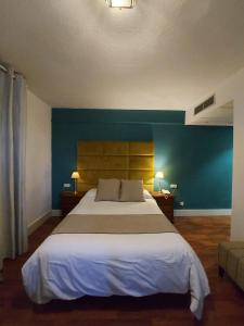 1 dormitorio con 1 cama grande y pared azul en Hotel Don Gonzalo, en Montilla