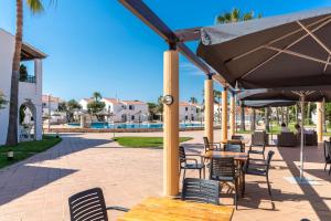 een patio met tafels en stoelen en een parasol bij Apartamentos Vistapicas in Cala en Blanes