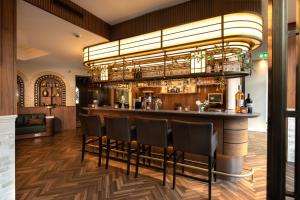 een bar met stoelen en een kroonluchter bij Grand Hotel Valies in Roermond