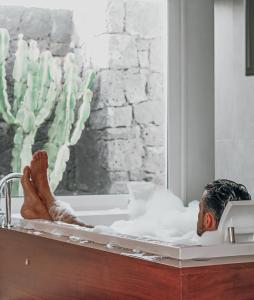 a man laying in a bath tub with his feet in it at Hyde Park Lane Villas in Puerto del Carmen