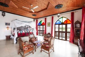 een kamer met een bed en stoelen en glas-in-loodramen bij Tembo House Hotel in Zanzibar City