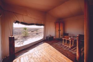 Zimmer mit einem großen Fenster in einem Zelt in der Unterkunft Dar Inacamp in El Mjed