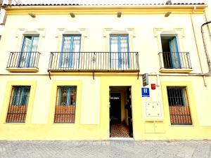 un edificio amarillo con balcones y una puerta en Hotel Conde de Cárdenas, en Córdoba